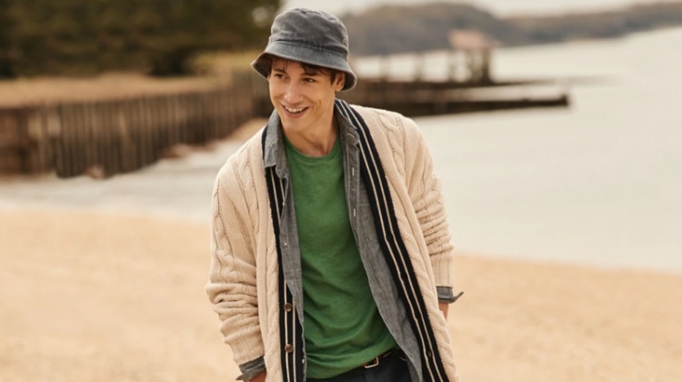 All smiles, Nicolas Ripoll wears a J.Crew cable-knit cardigan $125, chambray shirt $79.50, t-shirt $19.50, 10.5" chino shorts $65, and a bucket hat $39.50.