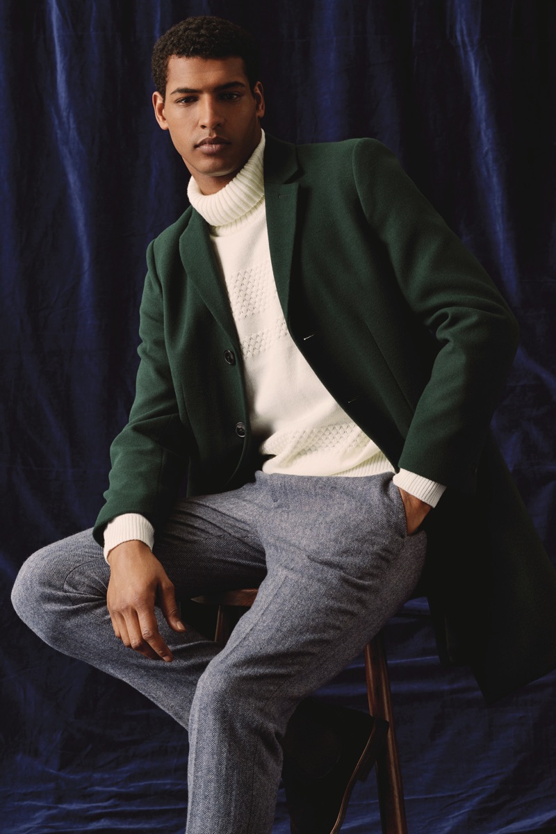 A sleek vision, Tidiou M'Baye wears a green coat with a turtleneck sweater and trousers by Burton.