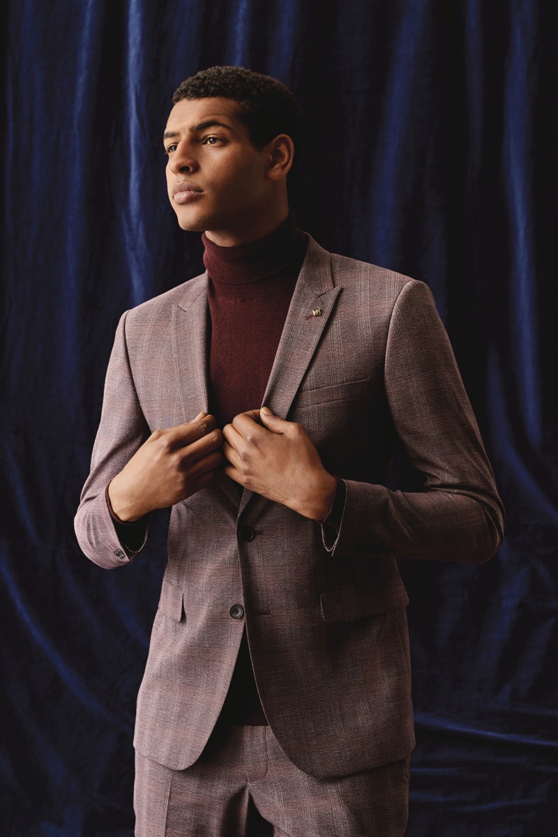 Embracing autumnal hues, Tidiou M'Baye dons a suit and turtleneck sweater from Burton.