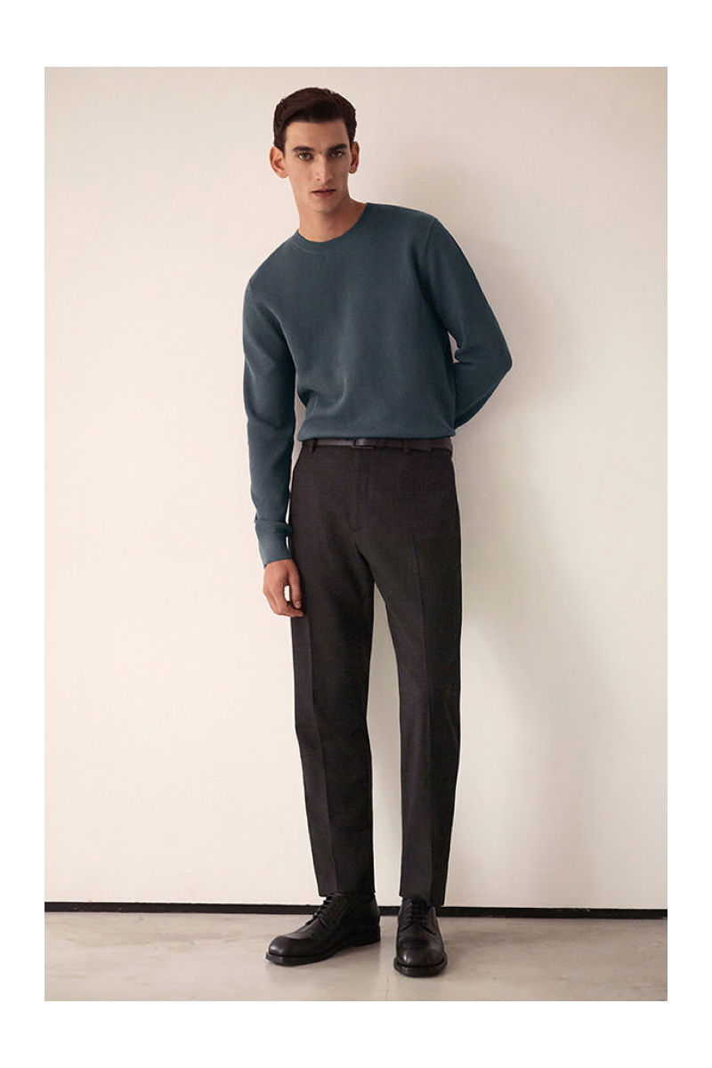 A smart vision, Thibaud Charon wears a fine knit sweater with pleated trousers by COS.