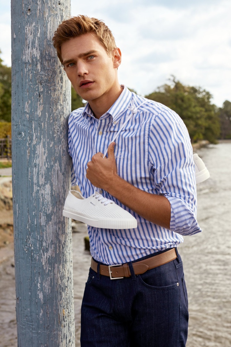 Bo Develius sports a striped oxford shirt with dark wash denim jeans by GANT.