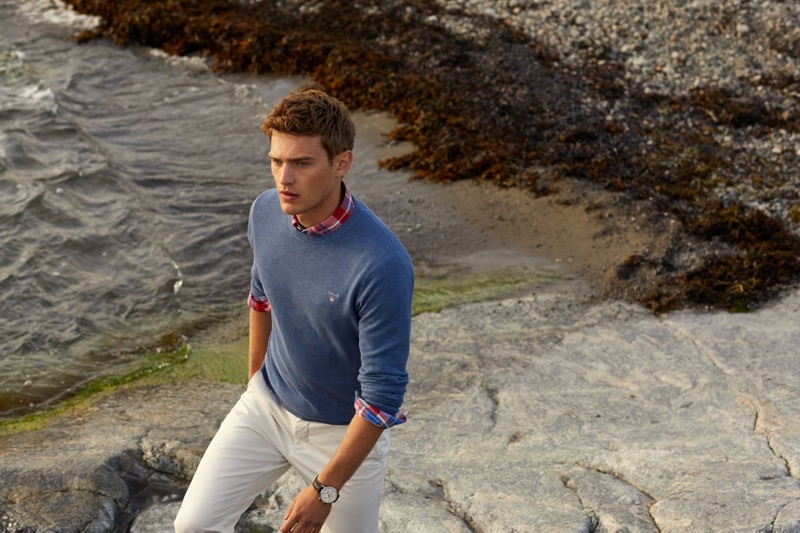 Taking a stroll, Bo Develius dons a sweater with a plaid shirt and chinos by GANT.