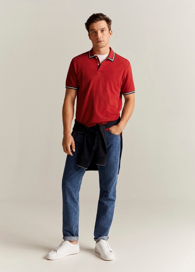 Front and center, Alexis Petit dons a red polo with dark wash denim jeans by Mango.