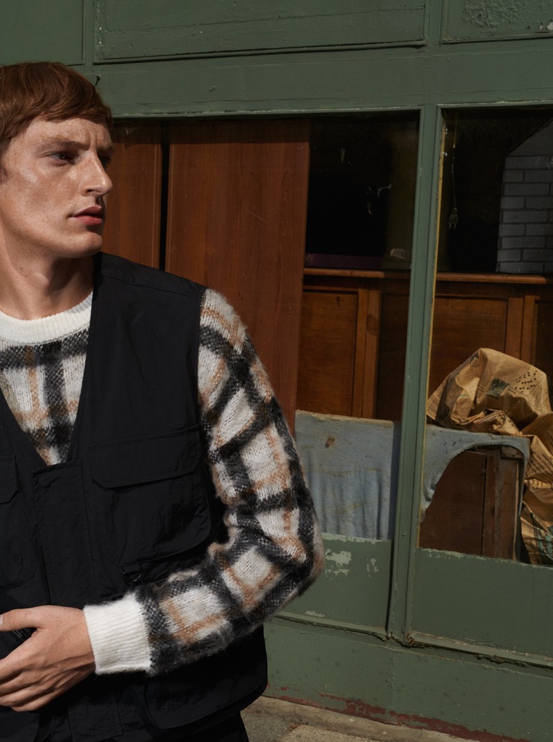 Model Roberto Sipos dons a checked sweater and utility vest from Reserved.