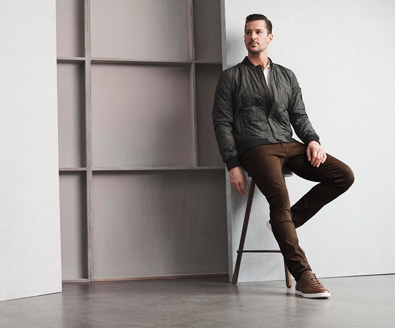 Sitting for a photo, Andrew Shaw models 34 Heritage's Cool mid-rise, slim leg brown pants.