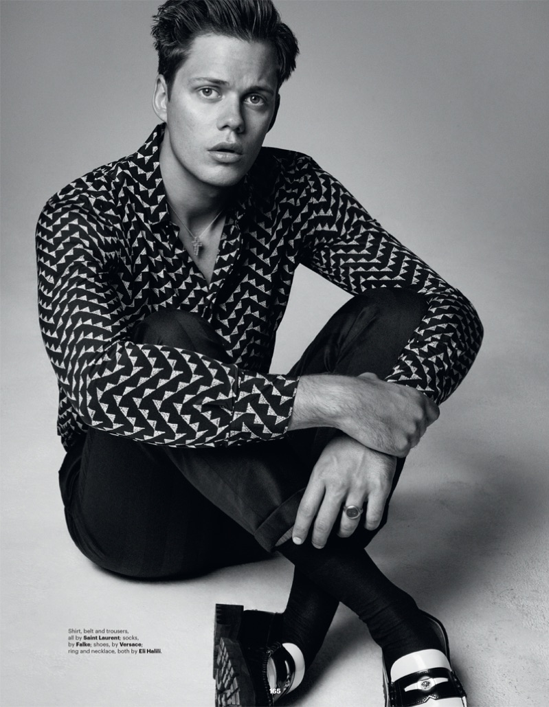 Taking to the studio, Bill Skarsgård rocks a shirt, belt and trousers by Saint Laurent. He also dons Versace shoes.