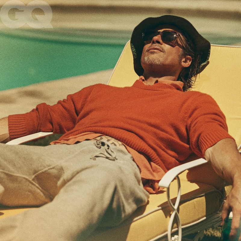 Soaking in the sun's rays, Brad Pitt wears a sweater by The Elder Statesman with a shirt and sweatpants from Stock Vintage. He also sports an Albertus Swanepoel hat, Jacques Marie Mage sunglasses, and a Tiffany & Co. bracelet.