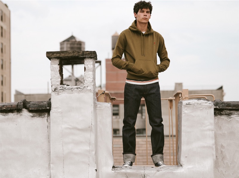 Showcasing a casual look, Tyler Blue Golden wears an AMI heart logo hoodie, Norse Projects striped tee, A.P.C. New Standard indigo jeans, and Converse Chuck taylor All Star '70s high top sneakers.