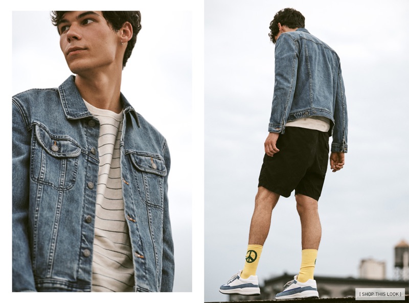 Taking to a rooftop, Tyler Blue Golden wears a Mollusk striped sweatshirt with an A.P.C. denim jacket, Save Khaki shorts, A.P.C. running sneakers, and Druthers socks.