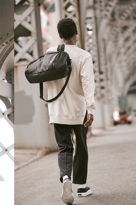 Youssouf Bamba dons a Y-3 sweater, cropped track pants, Tangutsu sneakers, and a gym bag.