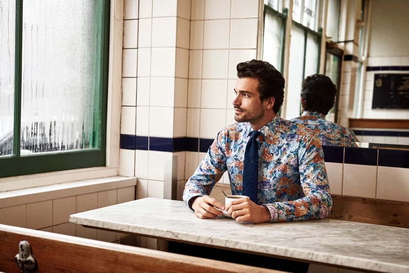 Enjoying a cup of coffee, Paul Kelly models a patterned shirt from Eton's holiday 2019 collection.