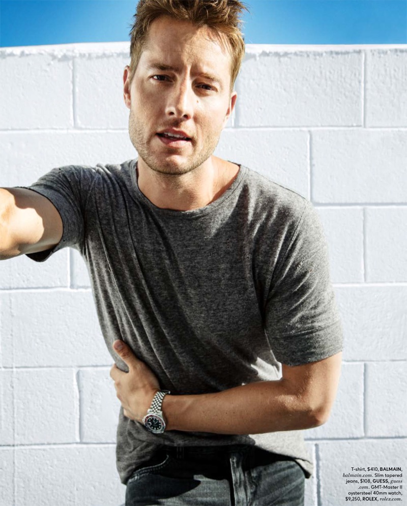 Posing for a DuJour photo, Justin Hartley rocks a Balmain t-shirt with GUESS jeans, and a Rolex watch.