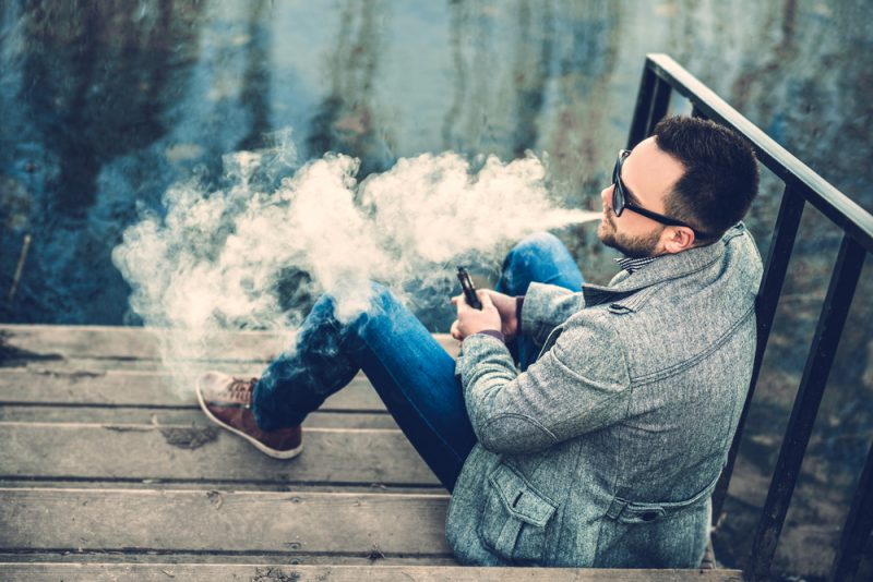 Man Vaping Outdoors in Sunglasses