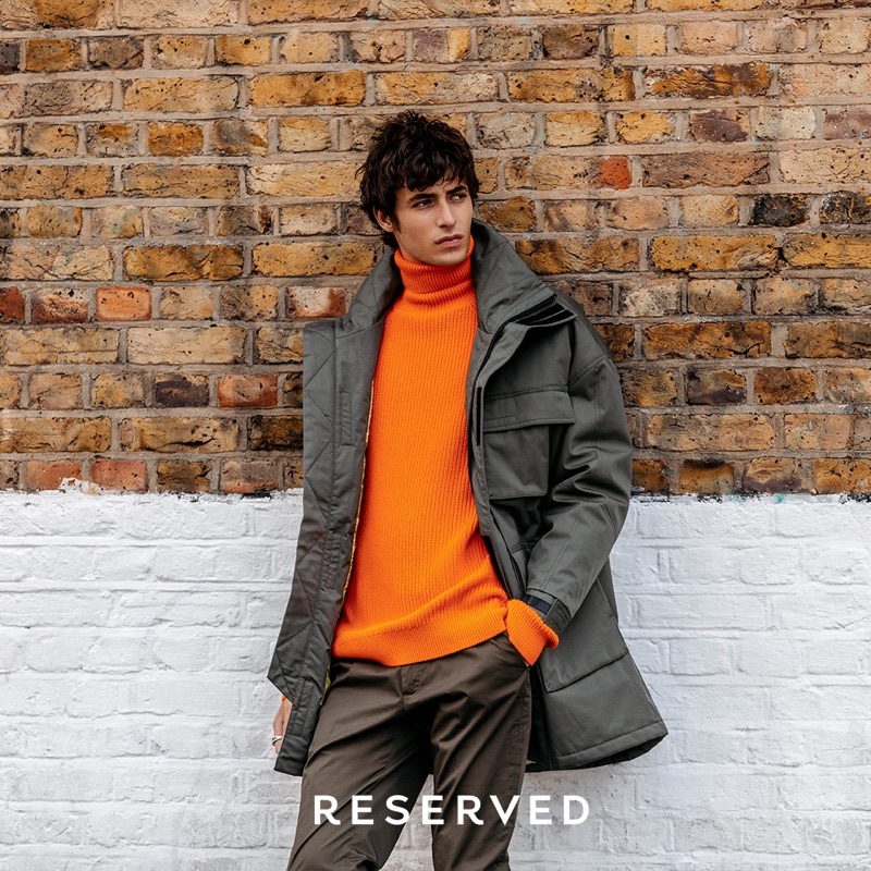 Making a stylish statement, Oscar Kindelan sports a parka with a ribbed orange turtleneck sweater. 