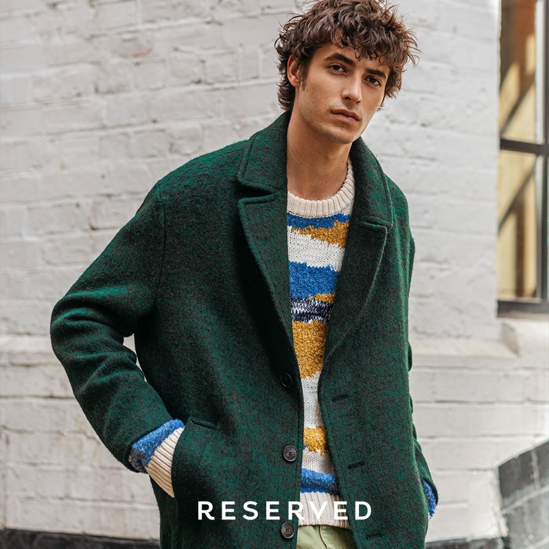 Oscar Kindelan dons a green coat with a graphic sweater from Reserved.