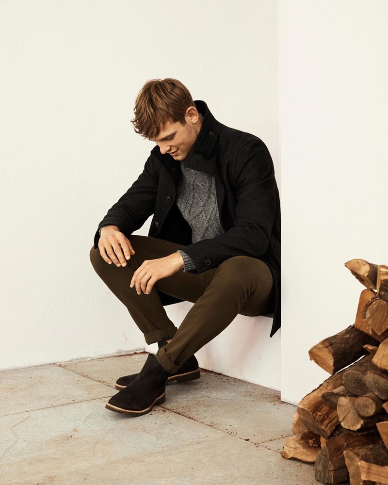 British model Elliott Reeder dons a gray cable-knit sweater with a black coat and chinos from Banana Republic.