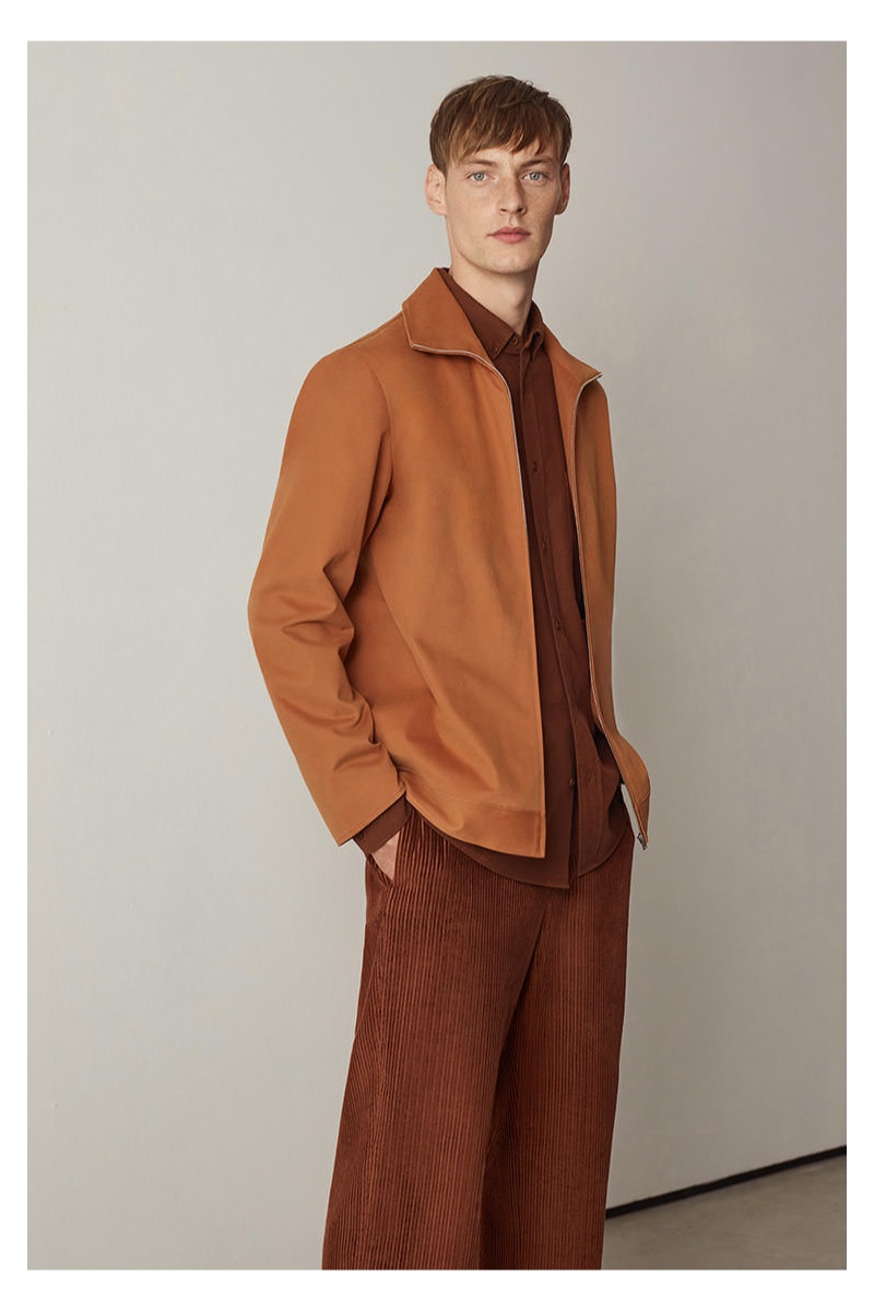 Connecting with COS, Roberto Sipos sports a full-zip shirt with wide-leg corduroy pants.