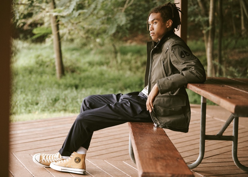 Bracing for the cold, Seth Hill models a Moose Knuckles Pearson jacket with AMI trousers, a striped tee by Frame, and Converse Chuck Taylor All Star '70s high top sneakers.