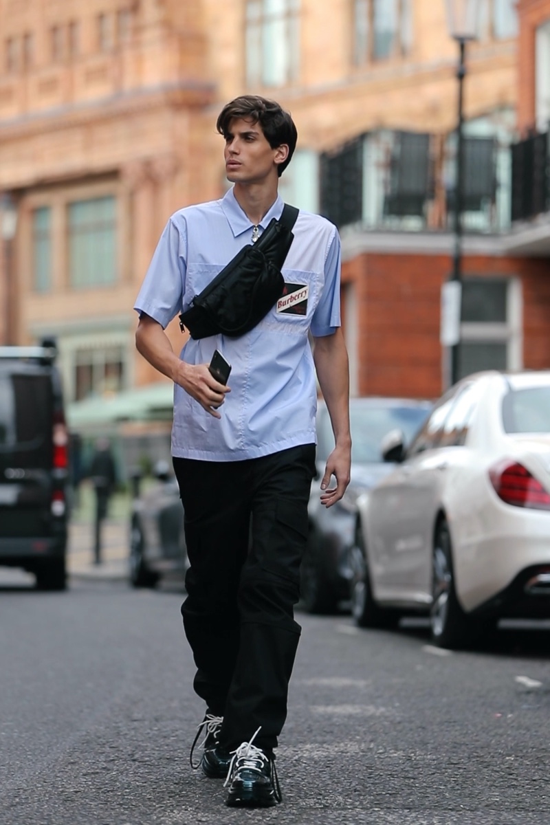 On the move, Gerard Sabe sports a Burberry short-sleeve logo shirt with Bottega Veneta cargo pants, Acne Studios sneakers, and a Valentino Garavani leather belt bag.