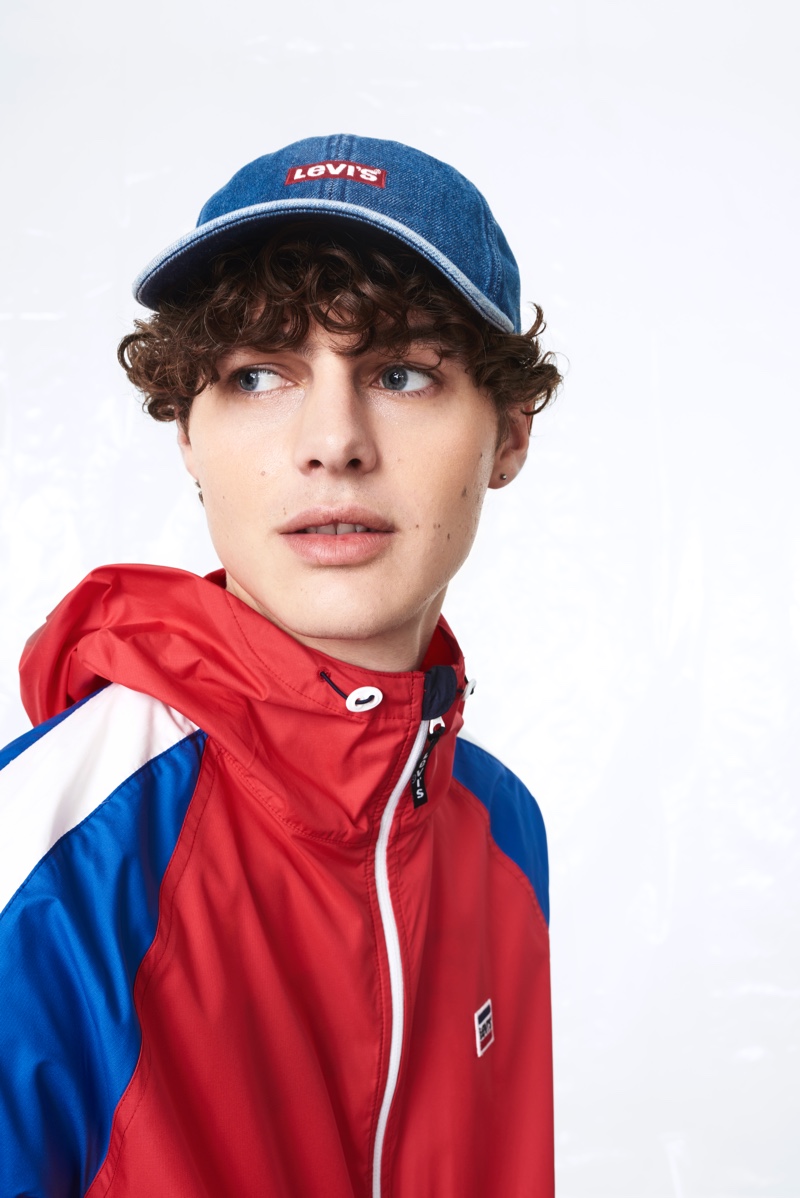 Taking to the studio with Levi's, Darwin Gray wears a logo cap with a color blocked windbreaker jacket.