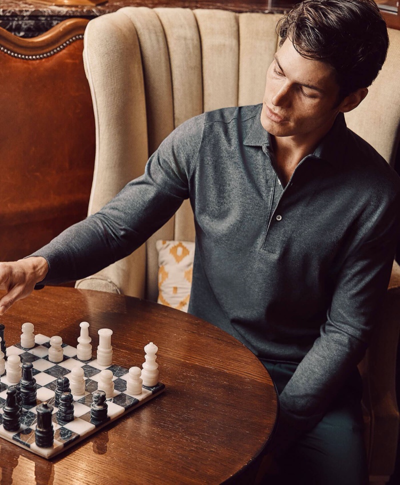 Playing a game of chess, Sam Way wears Luca Faloni's charcoal grey Brera polo shirt.