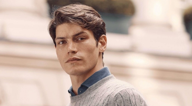 Connecting with Luca Faloni, Sam Way models a light grey cashmere cable knit sweater.