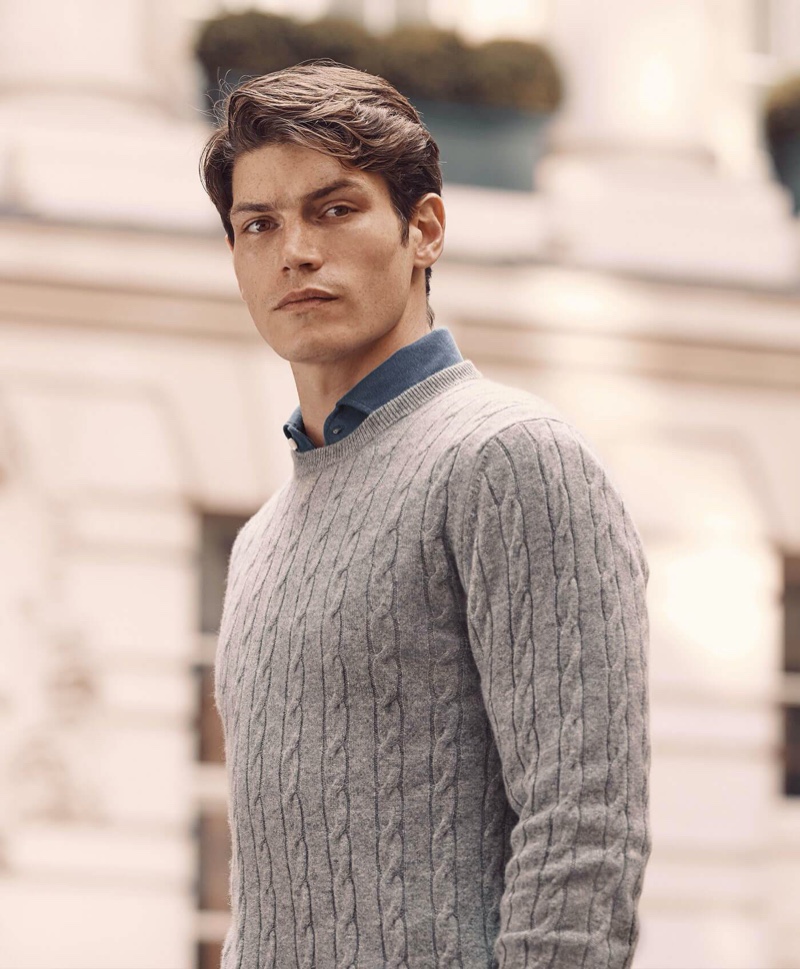 Connecting with Luca Faloni, Sam Way models a light grey cashmere cable knit sweater.