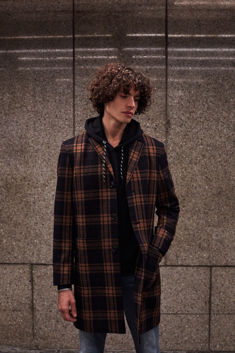 Donning a checked coat with a hoodie, Michael Cortina wears Ben Sherman.