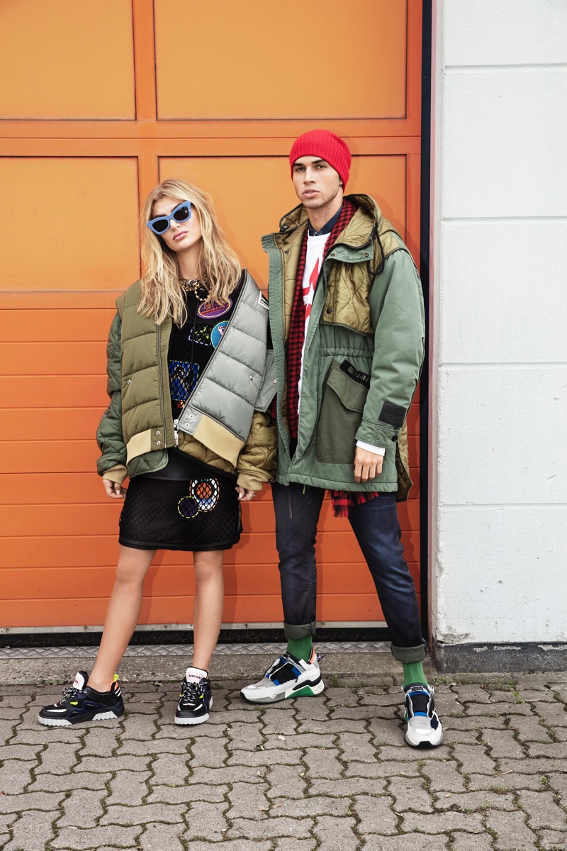 Appearing alongside Allie Fosheim, Daniel Angulo embraces a sporty look. The model dons a Diesel parka, sweatshirt, and jeans with a Wormland scarf. He also sports a HUGO knit beanie.