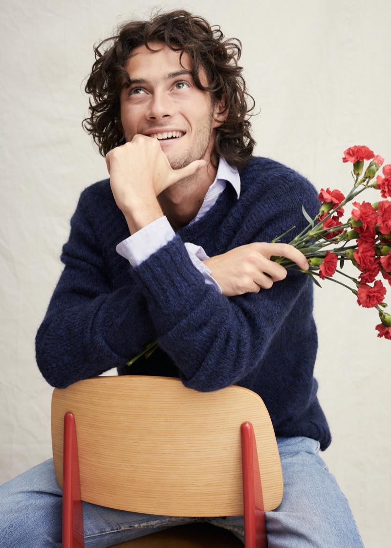 Pouring on the charm, Oli Green models a navy sweater with a button-down and jeans from Alex Mill.