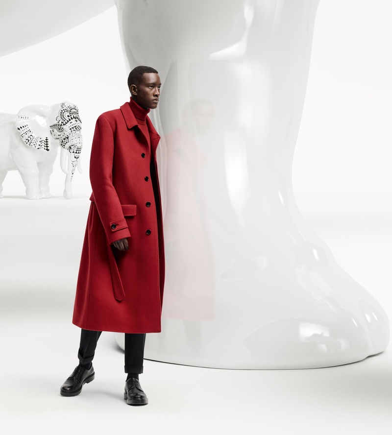 Making a statement in a red coat, Oumar Diouf fronts the BOSS x Meissen holiday campaign.