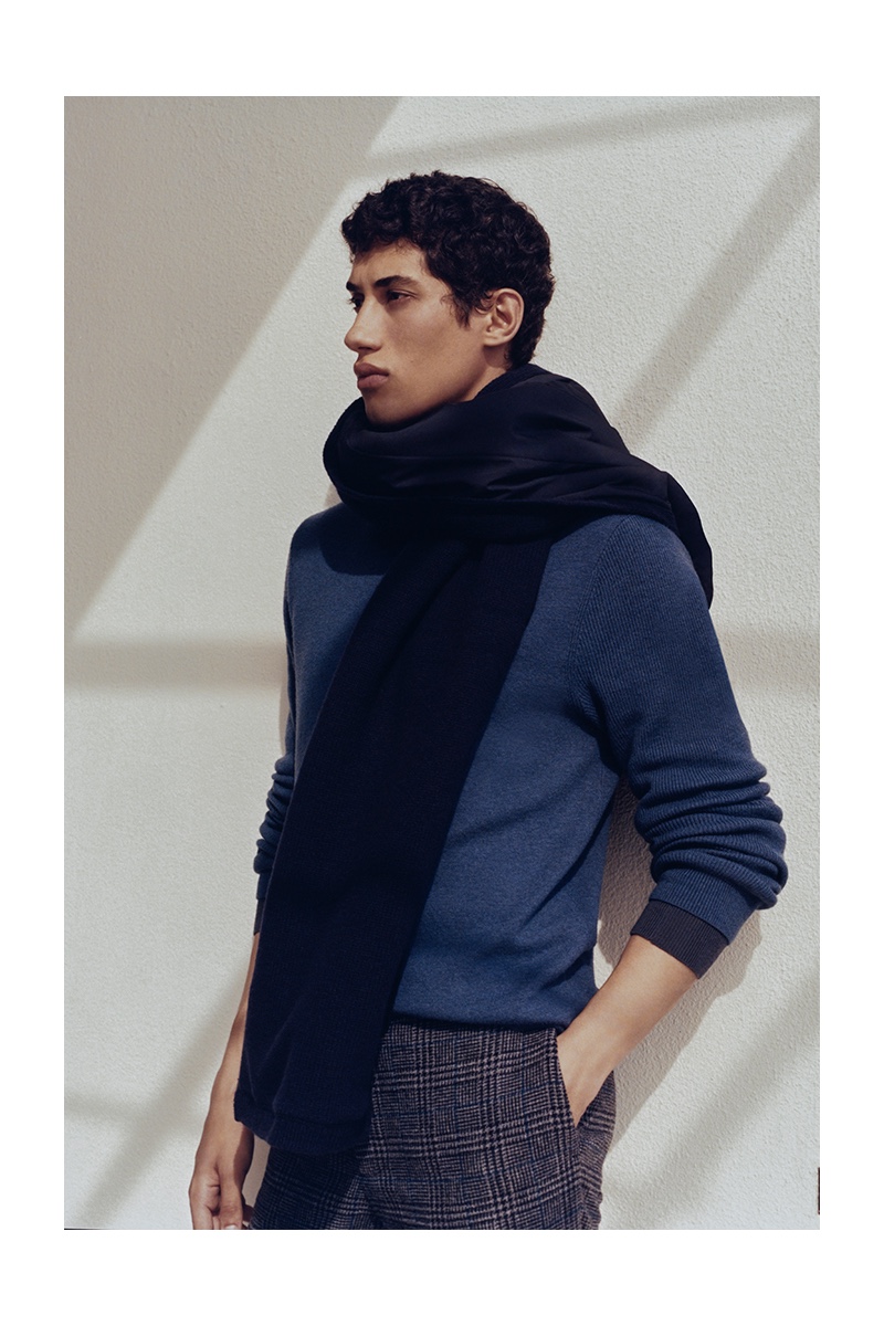 Front and center, Malik Al Jerrari dons an oversized scarf with a blue sweater  and glen plaid dress pants by Club Monaco.