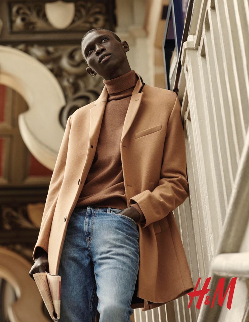 Fernando Cabral dons a camel-colored coat with a brown turtleneck sweater and light wash jeans from H&M.