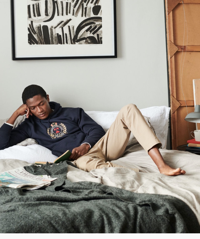 Relaxing in bed, Hamid Onifade dons a printed hooded sweatshirt from H&M.