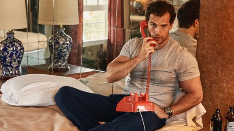 Taking a phone call, Henry Cavill dons an Armani Exchange t-shirt with Tommy Hilfiger pants, an Omega watch, and American Trench socks.