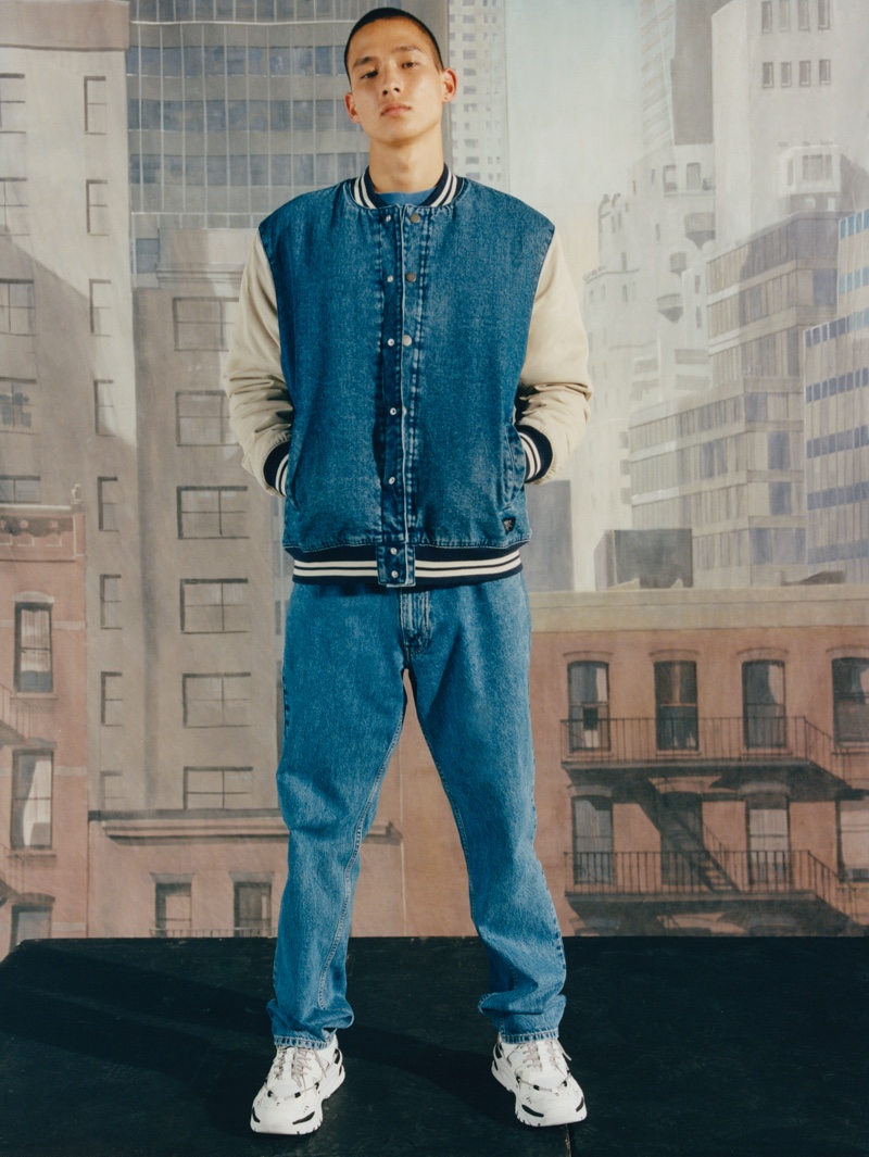 Connecting with Pull & Bear, Tommy Vanden Meerssche wears a denim varsity jacket and relaxed jeans.