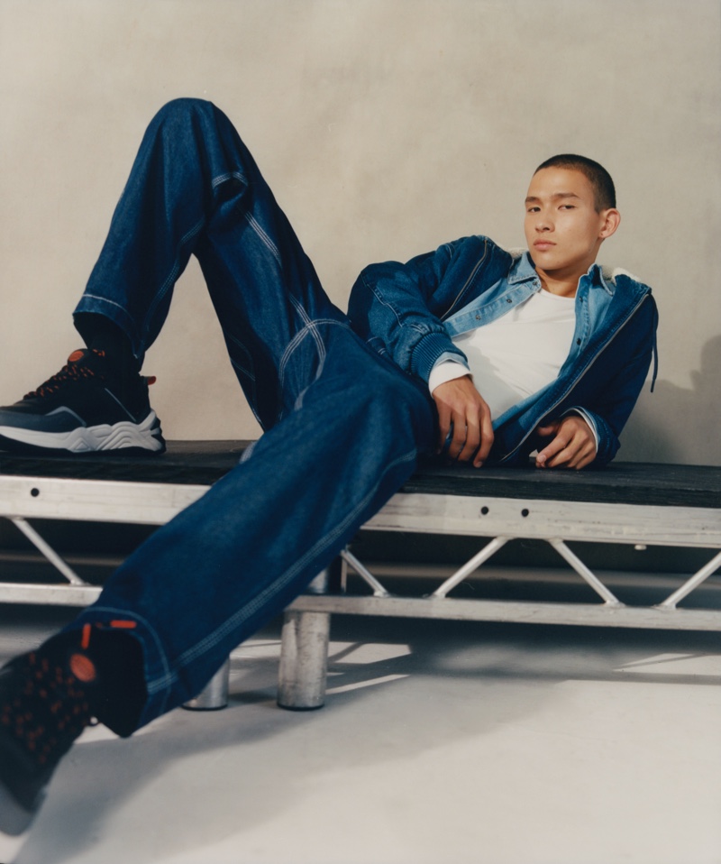 Posing for a photo, Tommy Vanden Meerssche sports a hooded denim jacket, shirt, and jeans from Pull & Bear.