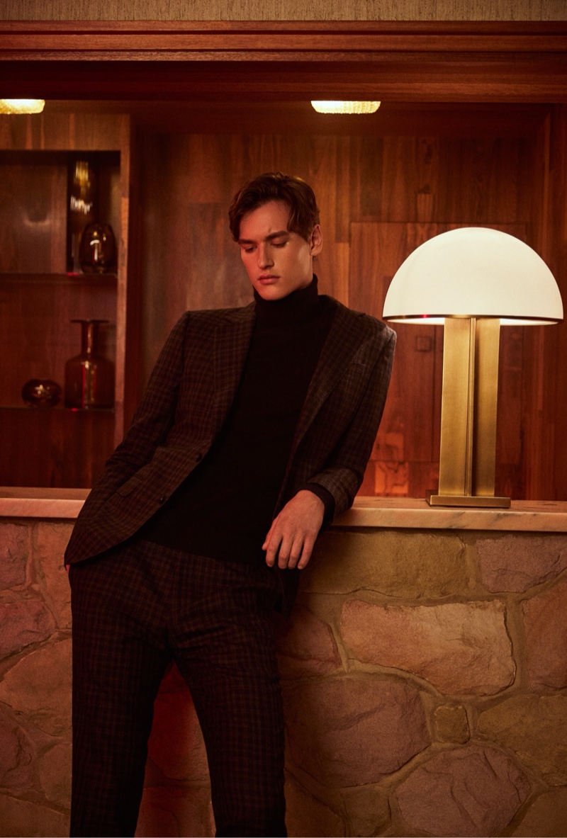 Posing by the bar, Jegor Venned wears Reiss' checked suit with a turtleneck sweater.