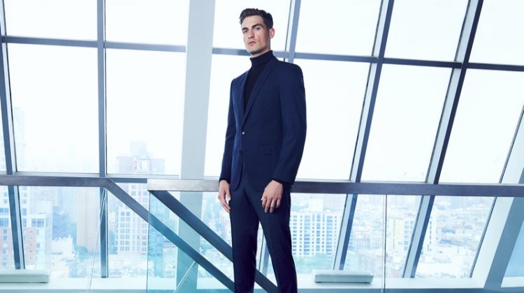 Jason Anthony dons a navy BOSS suit with a black turtleneck for Bloomingdale's.