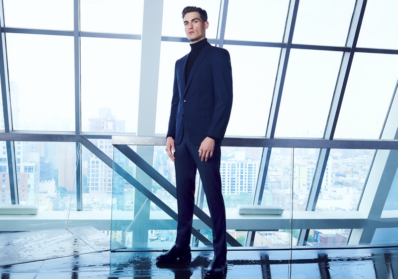 Jason Anthony dons a navy BOSS suit with a black turtleneck for Bloomingdale's.