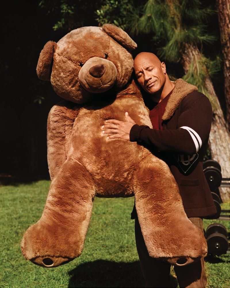 Hugging a giant teddy bear, Dwayne "The Rock" Johnson sports a Dolce & Gabbana cardigan, Brioni sweater, and Double RL jeans for WSJ. magazine.