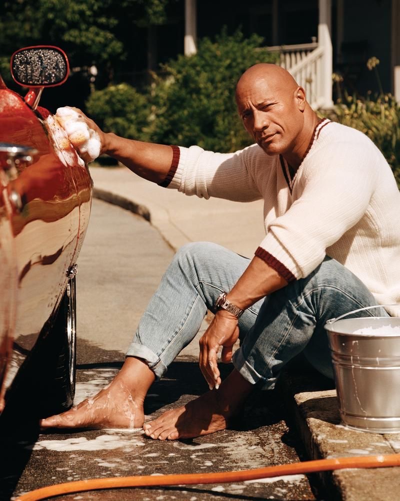 Photographed washing a car, Dwayne "The Rock" Johnson wears a Todd Snyder sweater with Levi's jeans and a Panerai watch.