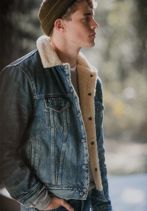 Connecting with East Dane, Jordy Baan wears a POLO Ralph Lauren sherpa collar denim trucker jacket and Varick slim-straight fit jeans. He also dons a Vince tee, Mollusk sweatshirt, and Filson knit beanie.