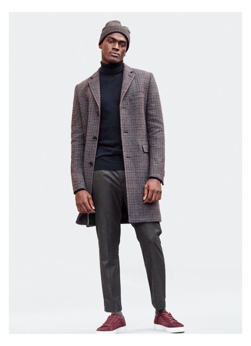 Hitting the studio, Davidson Obennebo models a H&M turtleneck with a checked coat and pleated trousers.