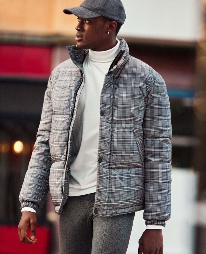 On the move, Davidson Obennebo sports a turtleneck with a checked puffer jacket and trousers from H&M.