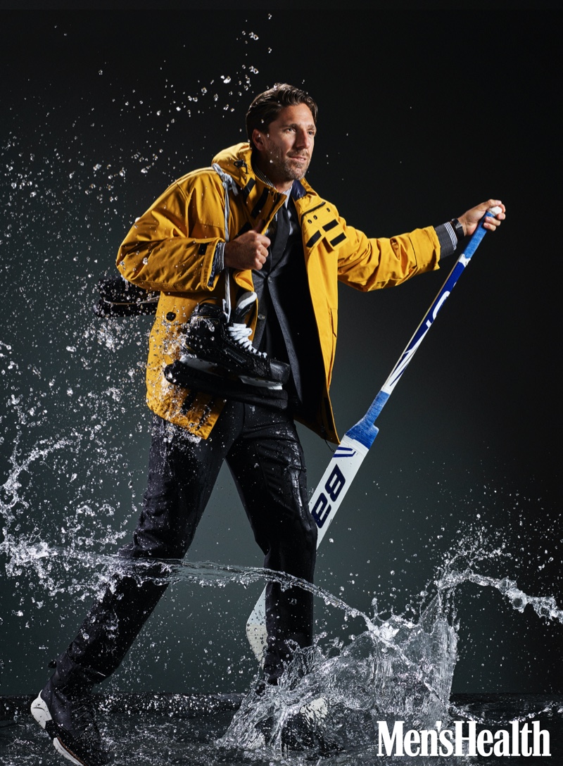 Connecting with Men's Health, Henrik Lundqvist sports a BOSS down jacket, suit jacket, shirt, and tie. Velient Align MX pants, Timberland sneaker boots, and a TAG Heuer watch complete his look. 