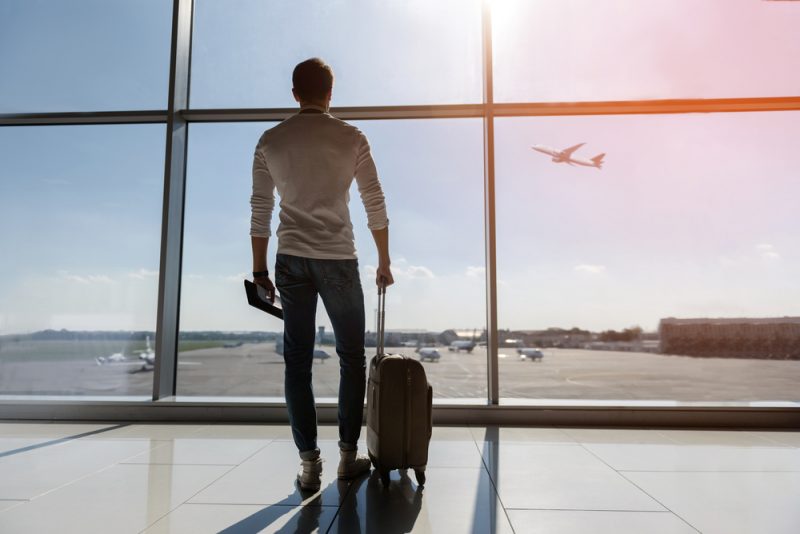 Man at Airport Watching Plane Takeoff