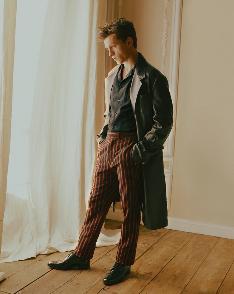 Starring in a GQ Style USA photo shoot, Tom Holland wears a shirt and coat by Versace. The young actor also dons striped pants by Ann Demeulemeester with Saint Laurent shoes.