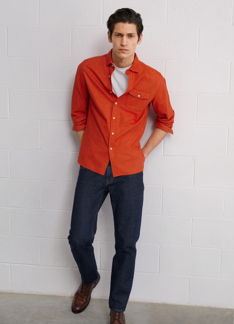 Embracing color, Justin Eric Martin sports a red shirt with dark wash denim jeans by Mango.