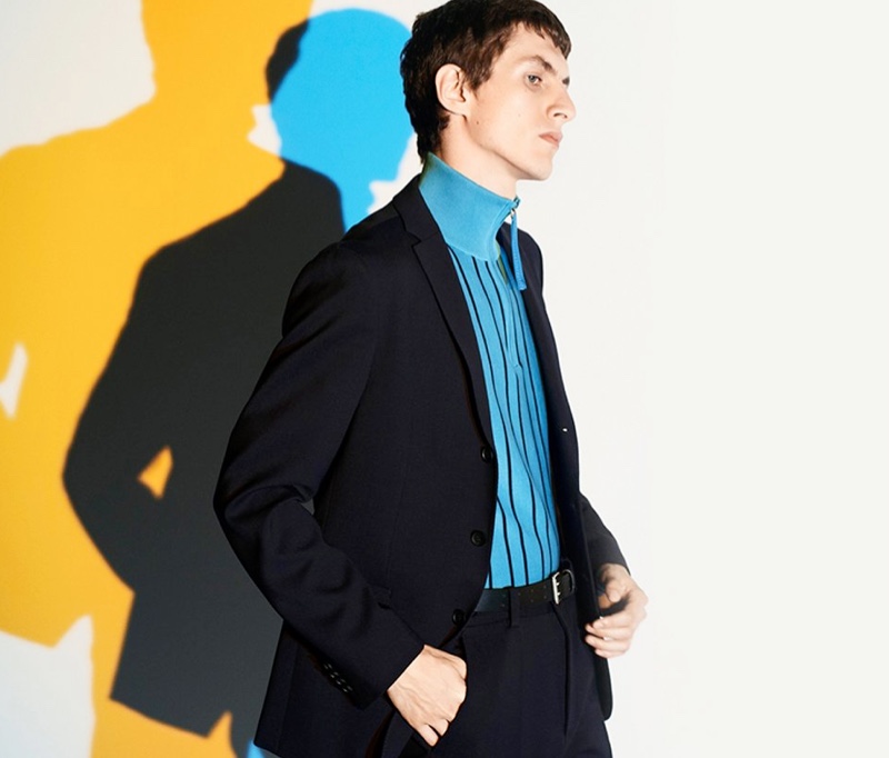 Henry Kitcher's black BOSS suit pops with a turquoise half-zip pullover.